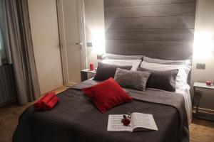 Un dormitorio con una cama grande con almohadas rojas y un libro en Il Pentagramma, en Cremona
