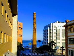 une grande cheminée à fumée en briques près des bâtiments et de l'océan dans l'établissement On the beach! Frente al Paseo Marítimo, Parking y Piscina, à Malaga