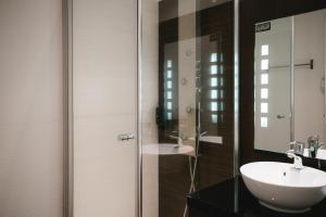 a bathroom with a sink and a glass shower at Zenia Hotel & Spa in Cambrai +19 photos