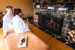 a man and woman sitting in front of a fireplace at Peppers Cradle Mountain Lodge in Cradle Mountain