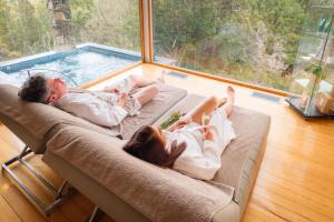 two people laying on a couch next to a pool at Peppers Cradle Mountain Lodge in Cradle Mountain