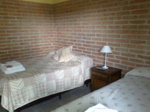 a bedroom with two beds and a brick wall at Hotel Las Termas in Bernardo Larroudé