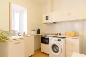 eine weiße Küche mit Waschmaschine in der Unterkunft Private House Only For You 133 - 8min historicCenter in Vila Nova de Gaia