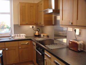a kitchen with wooden cabinets and a stove top oven at The Granary in The Square in Grantown on Spey