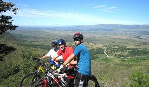 three people riding bikes on a hill with a view at Saint Michel Unidad Superior in Alta Gracia