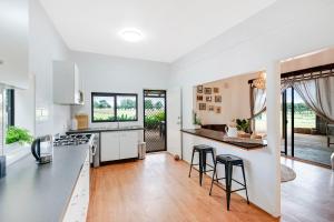 a kitchen with white cabinets and black counter stools at Farm & Co-sy by Kingscliff Accommodation in Cudgen
