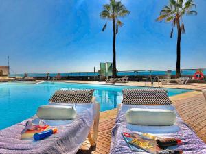 two beds next to a swimming pool with palm trees at Atlantic Ocean & Beach Views - Playa Del Cura in Las Palmas de Gran Canaria