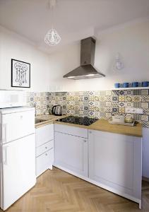 a kitchen with white cabinets and tiles on the wall at Dla Przyjaciół - Apartamenty nad morzem in Mosty