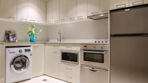 a kitchen with white cabinets and a washer and dryer at Oaks Gold Coast Hotel in Gold Coast