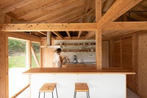 a kitchen in a wooden house with two stools at SHINMINKA Villa TAMASHIRO in Nakijin