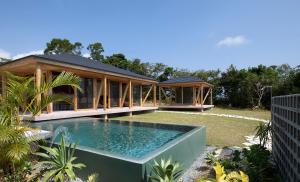 a house with a swimming pool in the yard at SHINMINKA Villa TAMASHIRO in Nakijin
