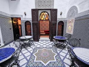 a patio with tables and chairs in a building at Riad Farah in Fès