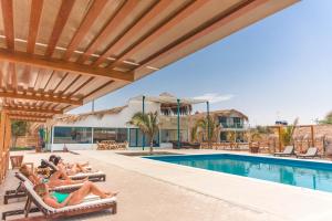 a group of people laying on lounge chairs next to a swimming pool at Kokoa Hotel Vichayito in Vichayito