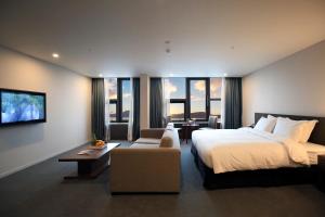済州市にあるベスト　ウェスタン　チェジュ　ホテルの大きなベッドとソファが備わるホテルルームです。