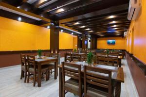 restauracja z drewnianymi stołami i krzesłami oraz żółtą ścianą w obiekcie Hotel Lake Star w mieście Pokhara