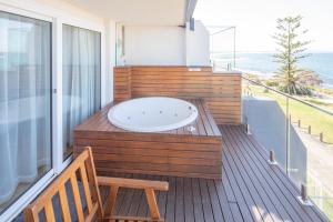 a hot tub on a balcony with a wooden deck at Ocean Front Motel in The Entrance