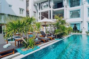 - une piscine avec des chaises et un parasol à côté d'un bâtiment dans l'établissement Anio Boutique Hotel Hoian, à Hội An