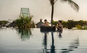 a couple of people sitting in a swimming pool at Grand Mirage Resort & Thalasso Bali - All Inclusive in Nusa Dua