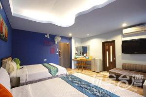 1 dormitorio con 2 camas y pared azul en Happiness Space, en Hengchun