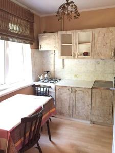 a kitchen with white cabinets and a table with chairs at Apartment in 2 mikrorayon in Almaty