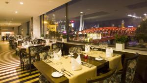 a restaurant with tables and chairs with a view of a bridge at Broadway Mansions Hotel - Bund in Shanghai