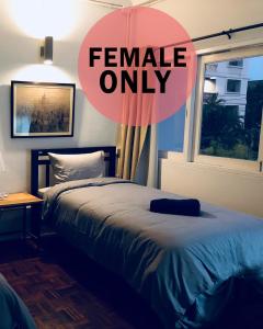 a bedroom with a bed and a window with the words female only at Pingplalee Female House in Bangkok