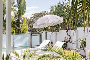 an outdoor patio with chairs and an umbrella at Cape Beach House in Byron Bay