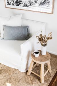 a coffee table next to a bed with a white bedspread at Cape Beach House in Byron Bay