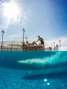 um homem sentado num banco ao lado de uma piscina em Feliz Hotel Boracay em Boracay