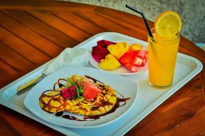 a tray with two plates of food and a glass of orange juice at The Sabho Garden in Nusa Penida
