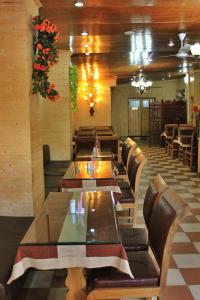 a restaurant with long tables and chairs and flowers at Walisons Hotel in Srinagar