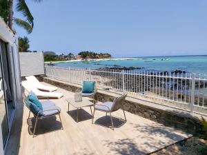 a beach area with chairs, a table, and a balcony at Les 2 canons in Flic-en-Flac