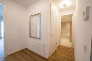 einen weißen Flur mit Spiegel und ein Badezimmer in der Unterkunft Moderne trifft Tradition im Herzen Wiens in Wien + 28 Fotos