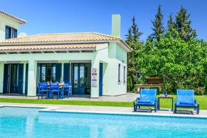 a house with blue chairs and a swimming pool at Villa Nissaki in Kaligata