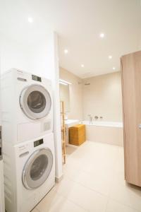 eine weiße Waschküche mit Waschmaschine und Trockner in der Unterkunft Moderne trifft Tradition im Herzen Wiens in Wien