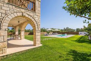 - un bâtiment en pierre avec une arche à côté d'une piscine dans l'établissement Villa Stagio, à Alykes