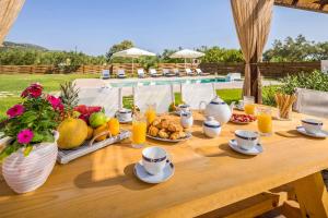 een houten tafel met een ontbijt van fruit en sap bij Villa Stagio in Alykes