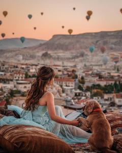 a woman sitting on a rock with a dog and hot air balloons at Agora Guesthouse in Istanbul