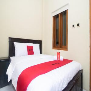 1 dormitorio con 1 cama con manta roja y blanca en RedDoorz Syariah near Universitas 17 Agustus Banyuwangi, en Banyuwangi