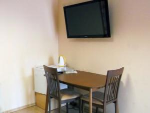 a dining room table with two chairs and a television on the wall at Kambarių nuoma - Rumšiškės SAURIDA in Rumšiškės