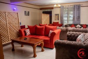 a living room with a red couch and a table at Comfort Guest House in Kericho
