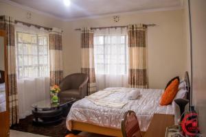 a bedroom with a bed and a chair and a table at Comfort Guest House in Kericho