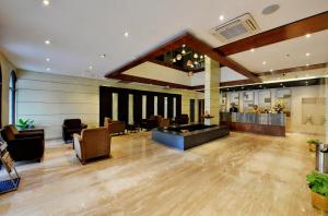 a lobby with a waiting area with chairs and tables at Hotel Ramanashree Richmond in Bangalore