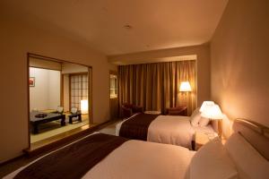 a hotel room with two beds and a desk at Hotel New Nagasaki in Nagasaki