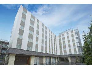 镰仓市Sotetsu Fresa Inn Kamakura-Ofuna Higashiguchi的一座白色的大建筑,背后是天空