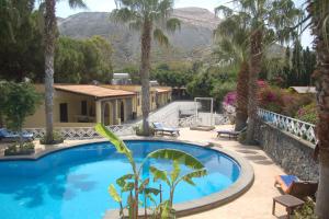 - une piscine en face d'une maison avec des palmiers dans l'établissement Hotel Al Togo Fitness & Relax, à Vulcano