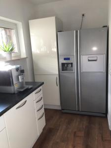 una cocina con nevera de acero inoxidable y armarios blancos en Landhaus, en Heppenheim an der Bergstrasse