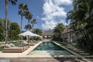 a villa with a swimming pool and palm trees at Villa Massilia Bali in Seminyak