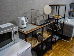 a kitchen with a microwave and two shelves with food at Cent Hostel in Lublin