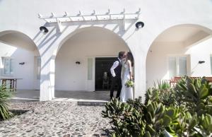 Una novia y un novio parados bajo un arco en su boda en Eos Villa, en Imerovigli